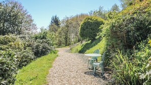 A gravel path leading through a garden with a table and chairs, surrounded by various plants and trees. - 6 Priory (Shanklin)