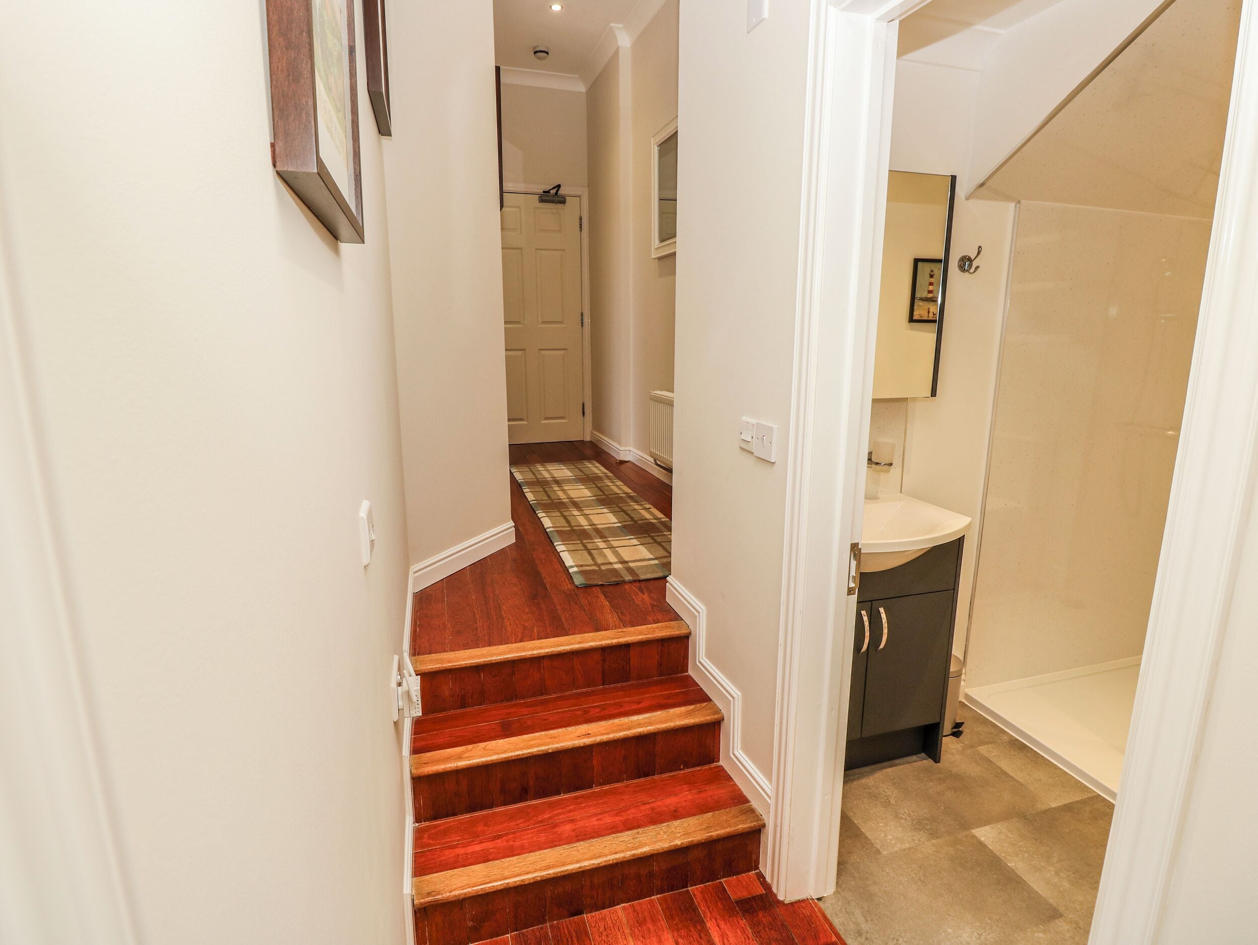 Una escalera con un suelo de cuadros que lleva a un baño con un lavabo y un armario.