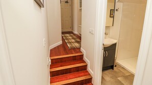 A staircase with a checkered carpet leading to a bathroom with a sink and cabinet. - 6 Priory (Shanklin)
