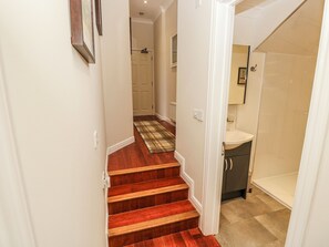 Una scala con una moquette a scacchi conduce a un bagno con un lavabo e un armadietto.