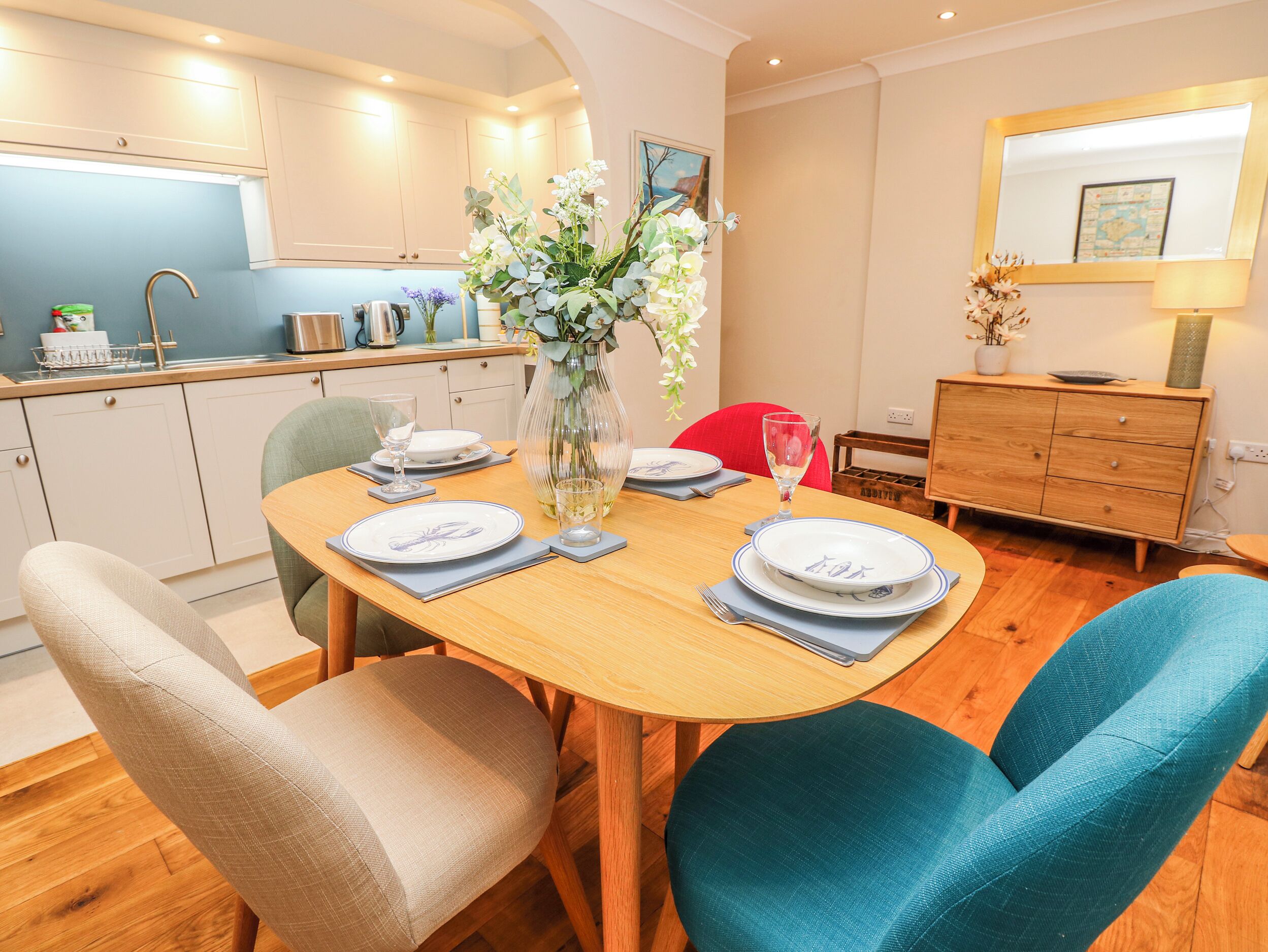 Un comedor con una mesa de madera, sillas y un jarrón con flores.