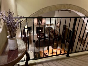 A balcony with a wrought iron railing, a vase with dried flowers, and a view of a living room with a fireplace, sofa, and table. - The Chimney (Bamburgh)
