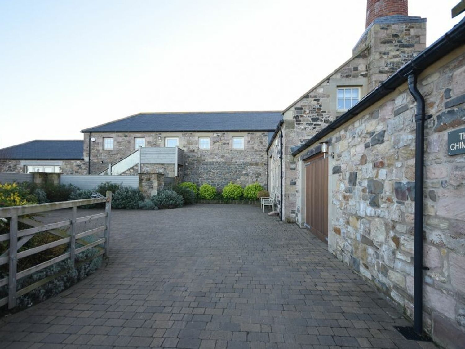 A stone building with a paved courtyard, a wooden fence, and a sign that reads 'The Chinese.'