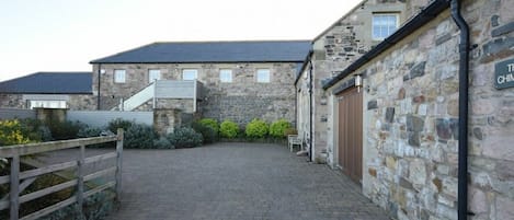 A stone building with a paved courtyard, a wooden fence, and a sign that reads 'The Chinese.'