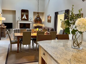 A modern living room with a dining area, a fireplace, and a large mirror. - The Chimney (Bamburgh)