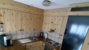 Een koelkast, een oven, een vaatwasser, kookgerei, borden en bestek