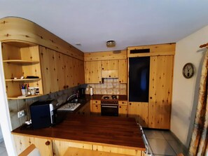A compact kitchen with wooden cabinets, a built-in oven, and a sink. - Chalet Guardaval, (Samnaun-Compatsch) by Interhome (Samnaun)