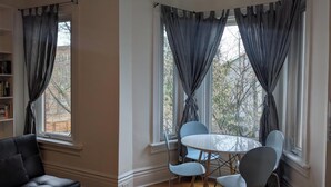 Ein Zimmer mit einem runden Tisch und Stühlen, einem Sofa und einem Bücherregal.