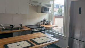 Eine kompakte Küche mit Herd, Mikrowelle und Kühlschrank, mit Blick auf Gebäude.