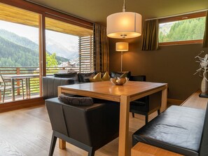 A modern dining area with a wooden table and black chairs, a bench, and a large window offering a mountain view. - Das Felaria, (Samnaun-Laret) by Interhome (Samnaun)