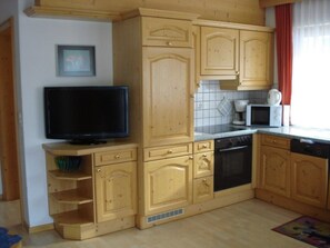 A kitchen with wooden cabinets, a television, a microwave, and a dishwasher. - Chasa Valetta, (Samnaun-Laret) by Interhome (Samnaun)