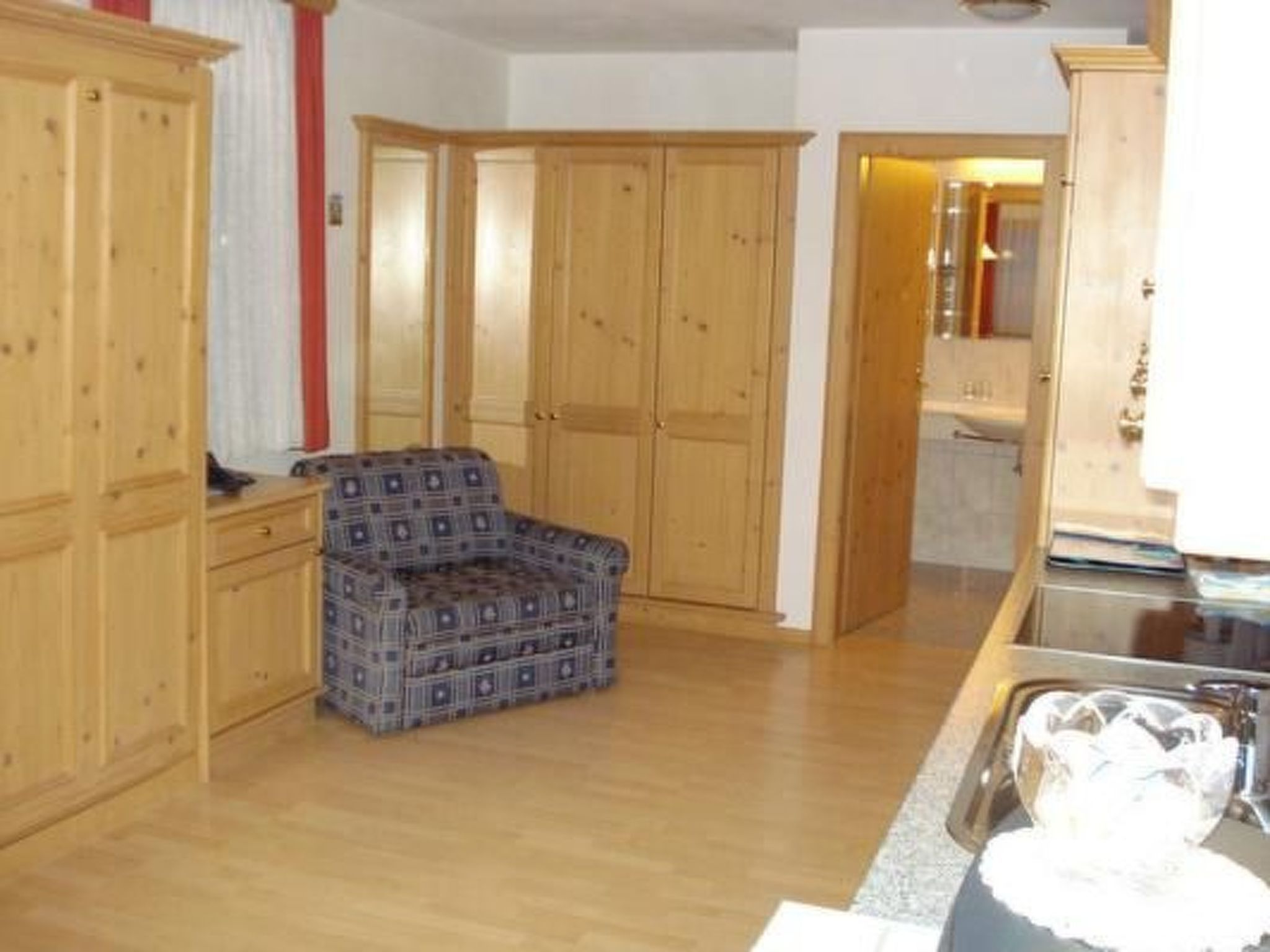Eine Küche mit Holzausstattung, einem gemusterten Stuhl und einem Spülbecken.