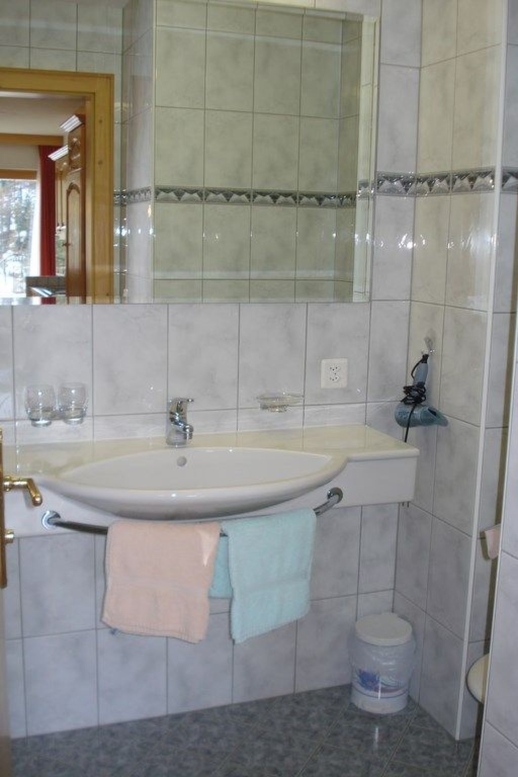 Un bagno con lavandino, specchio e pareti piastrellate.