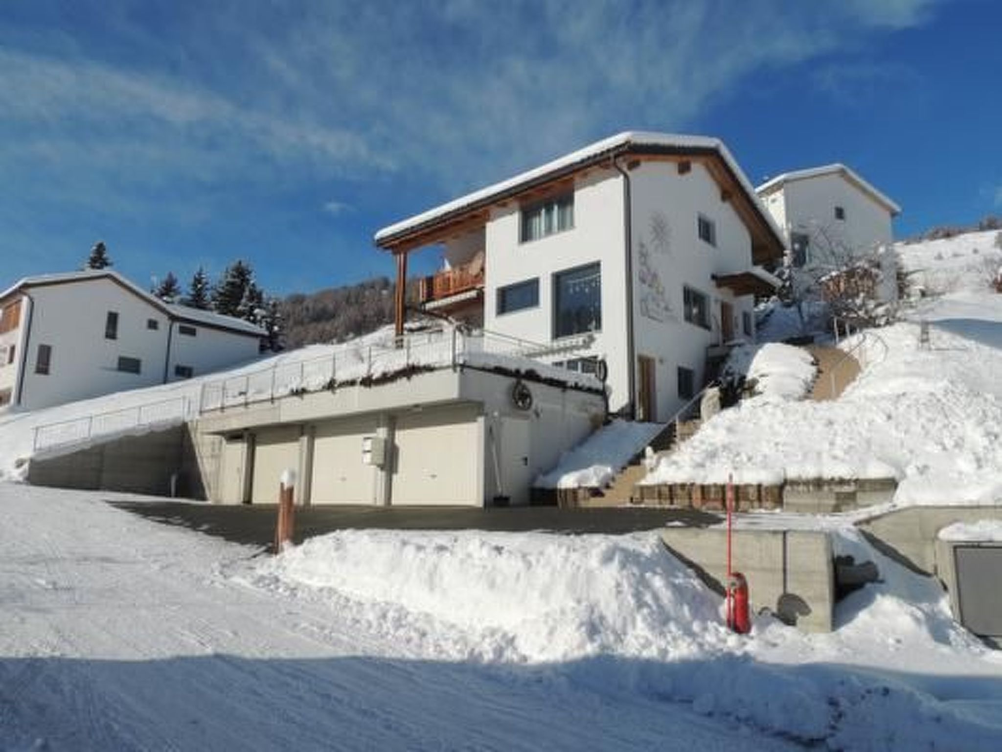 A multi-story building with a sloped roof, a covered outdoor area, and a snow-covered landscape.
