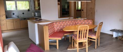 A modern kitchen with a dining area, wooden furniture, and a view of the outdoors.