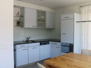 Eine moderne Küche mit weißen Schränken, einem Holztisch und einem eingebauten Geschirrspüler.
