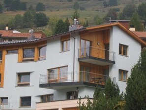 Un edifici d'apartaments de diversos pisos amb balcons, grans finestres i terrat pla.