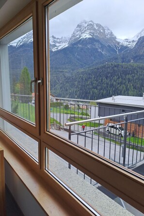 Ein Zimmer mit Fensterblick auf eine Berglandschaft.