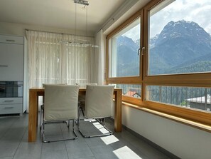 Eine moderne Küche mit Essbereich, einem großen Fenster und Bergblick sowie einer Deckenleuchte.