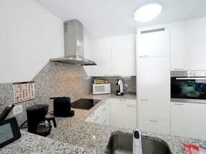 Eine moderne Küche mit weißen Schränken, einer Edelstahl-Dunstabzugshaube, einer Mikrowelle und einem Backofen.