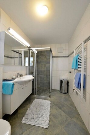 Ein Badezimmer mit Dusche, Waschbecken, Spiegel und Handtuchhalter.