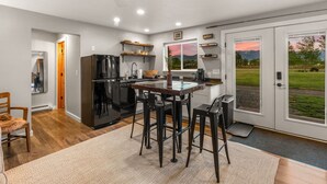 A modern kitchen with a bar area, built-in appliances, and a view through the glass doors.