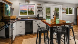 A kitchen with a wooden island, white cabinetry, and a view of the outdoors.