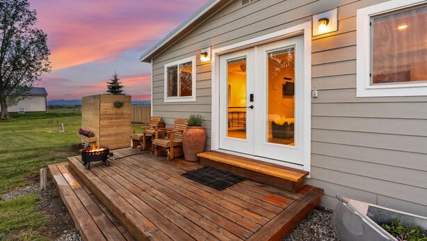 A house with a deck, a fire pit, outdoor seating, and a large window.