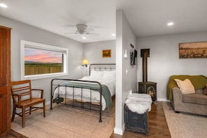 Un dormitorio con cama, una silla, un sofá, chimenea y un amplio ventanal con vistas.