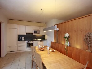 A modern kitchen with a wooden dining table, a microwave, and a built-in oven. - Apart Lischana, (Samnaun-Laret) by Interhome (Samnaun)