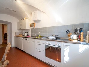 A modern kitchen with white cabinetry, a built-in oven, and a countertop with various kitchen utensils. - Ferienwohnungen Chasa Werro, (Sent) by Interhome (Sent)