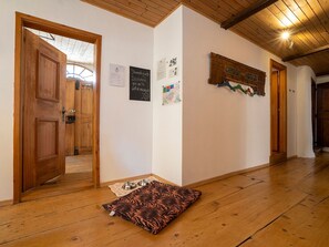 A hallway with wooden flooring, a wooden door, and a wall with various notices and a coat rack. - Ferienwohnungen Chasa Werro, (Sent) by Interhome (Sent)
