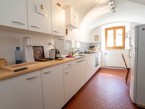 A kitchen with white cabinets, a wooden countertop, and a hexagonal tile floor. - Ferienwohnungen Chasa Werro, (Sent) by Interhome (Sent)
