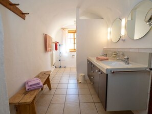 Ein Badezimmer mit einer Sitzbank, einem Waschbecken und einem Spiegel.