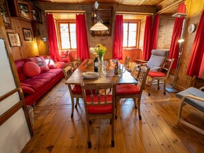 Ein gemütliches Holzinterieur mit einem Esstisch, der für vier Personen gedeckt ist, umgeben von roten Sitzmöbeln und einem roten Sofa.