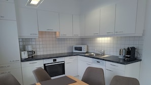 Una cocina moderna con armarios blancos, microondas, cafetera y lavavajillas.
