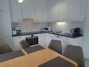 Eine moderne Küche mit weißen Schränken, einer Mikrowelle, einer Kaffeemaschine und einem Geschirrspüler.