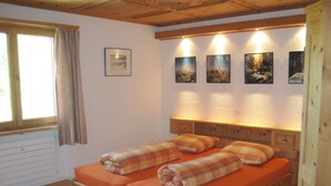 Quarto com cama, janela e quadros pendurados na parede.
