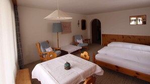 Ein Zimmer mit zwei Betten, einem Tisch mit einer Lampe und einem Stuhl.