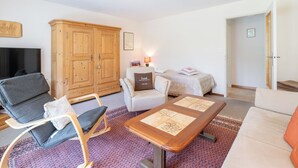 A living room with a sofa, a chair, a wooden cabinet, a television, and a small table. - HÄMMIG, (Scuol) by Interhome (Scuol)