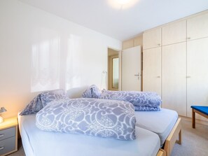 Une chambre avec deux lits, une table de chevet, une lampe et une armoire.