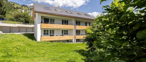 Une maison moderne à deux étages, dotée d’un toit en pente, de grandes fenêtres et d’une terrasse en bois.