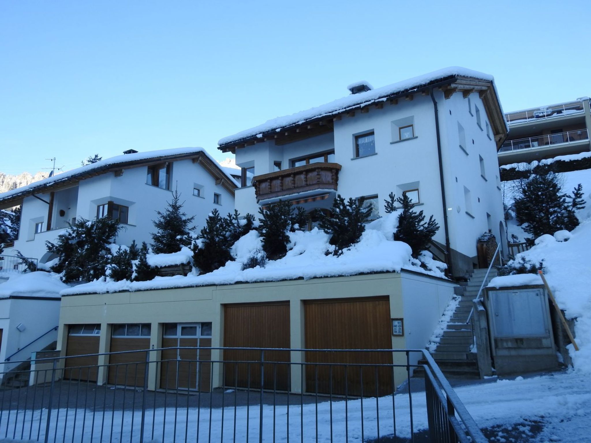Ein mehrstöckiges Gebäude mit schneebedeckten Dächern und einer Treppe, die zum Eingang führt.