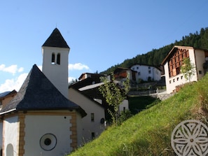 Un village rural doté d’une architecture traditionnelle, avec notamment une église surmontée d’un clocher et une maison au toit en pente.