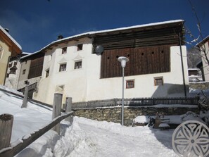 Un edifici tradicional amb fonament de pedra, persianes de fusta i teulada coberta de neu.