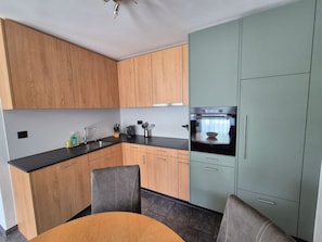 Une cuisine moderne avec des meubles en bois, un plan de travail noir et un four encastré.