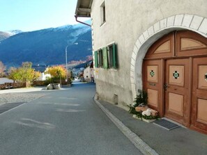 Un edificio con una amplia entrada en arco, una montaña al fondo y cielo despejado.
