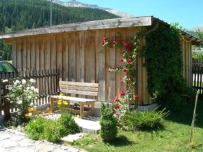 A wooden cabin with a bench and a garden with flowers. - Melcher Jon & Brigitte - Bauernhaus, (Valchava) by Interhome (Valchava)