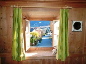 A wooden room with a window, curtains, and a small dog. - Melcher Jon & Brigitte - Bauernhaus, (Valchava) by Interhome (Valchava)