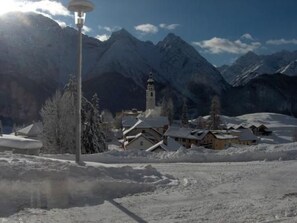A snow-covered village with a church and a bell tower, surrounded by mountains. - Fionas 257, (Ftan) by Interhome (Ftan)